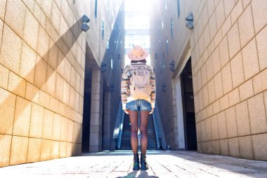 Omzunda sırt çantasıyla gezen genç bir gezginin, şehirde gezen şık bir yabancının arka görüntüsü. Sırt çantalı kız..