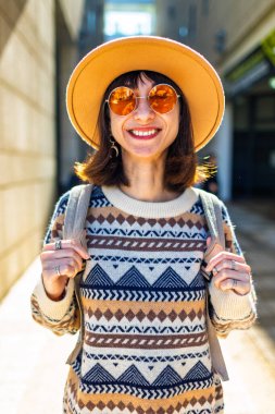 Sırt çantalı kız. Gün batımında Avrupa caddesinde yürüyen mutlu genç bir kadın. Sırt çantalı bir bayan gezgin şehri keşfediyor, şık bir yabancı şehirde dolaşıyor..