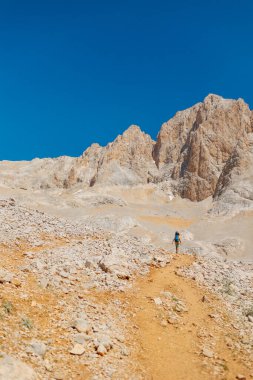Yaz kampı. Sırt çantalı çocuk. Çocuk sırt çantasıyla dağlarda geziyor. Yüksek dağlarda yaz yürüyüşü. Bir çocuk dağ yolunda yürüyor. Türkiye.