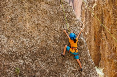 Yaz kampında spor. Bir çocuk yaz kampında kaya tırmanışı yapıyor. Dağcı çocuk. Doğada spor. Sevimli genç, kayaya bağlanmış bir şekilde tırmanıyor. Boş zaman. Yaz tatili