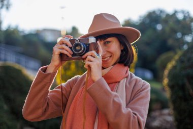 Kameralı genç bir kadın. Kameralı hippi turist kadın. Kız film kamerasıyla fotoğraf çekiyor. Yaşam tarzı konsepti. Film kamerası. Şık görünüş.