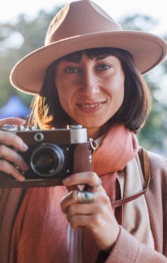 Kameralı genç bir kadın. Kameralı hippi turist kadın. Kız film kamerasıyla fotoğraf çekiyor. Yaşam tarzı konsepti. Film kamerası. Şık görünüş.