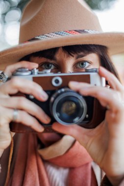 Kameralı genç bir kadın. Kameralı hippi turist kadın. Kız film kamerasıyla fotoğraf çekiyor. Yaşam tarzı konsepti. Film kamerası. Şık görünüş.