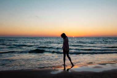 Yaz havası. Sahildeki kız. Pembe gömlekli ve mayolu mutlu genç kız sahilde dinleniyor. Mutlu kadın. Kız kumsalda duruyor. Kumsalda dinlenmek.