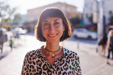 Leopar desenli bluz giyen neşeli genç bir kadın bir yaz günü sokakta yürür. Şehirde yürü..