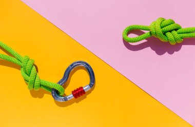 rope with a secure knot and a carabiner lies on a colored background. Equipment for rock climbing and mountaineering. reliable connection. Safety rope. concept of reliability and strength.