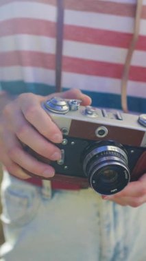 Dikey çekim. Genç bir kız kamera kullanıyor. Fotoğrafçı kamerayı ayarlar. Film kamerası olan şık bir kız. Film kamerası kapat. Maceralar ve seyahat.