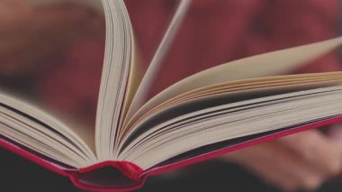 Kitabı kapat. Kadın eli çok hızlı bir şekilde kitabın sayfasını çevirir, kız kitabın doğru sayfasını arar. Elinde kitap olan bir kız..