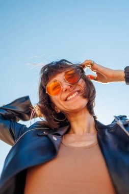 Rock konserinde dans eden ve müzik seven bir kız deri ceketli şık bir kız açık havada dans eden, rock müzik yapan, güneş gözlüklü mutlu bir kadın..