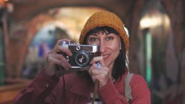 Genç, güzel, gülümseyen, kameralı, şık elbiseli bir hippi kadın. Sırt çantalı kaygısız kadın kamerasıyla fotoğraf çekiyor. Kameralı turist.