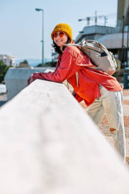 Açık hava yürüyüşü. Şehirde gezen neşeli, şık bir bayan turist. Şehri gezen, seyahat eden ve tatil yapan bir turist. Sırt çantalı kız.