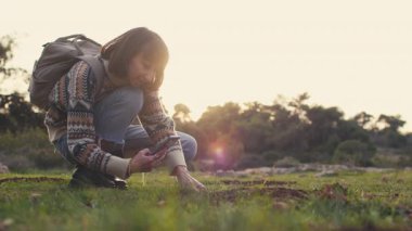 Kız doğa yürüyüşü yaparken çiçeklerin fotoğraflarını çekiyor. Kız telefonda doğanın fotoğraflarını çekiyor. Yüksek kalite 4k görüntü