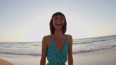 Mutlu kadın gülümsüyor ve sahilde eğleniyor. Genç ve güzel bir kızın yaz portresi. Güneş gözlüklü genç kız. Kız yaz tatilini denizde geçiriyor. Kumsalda dinlenmek..