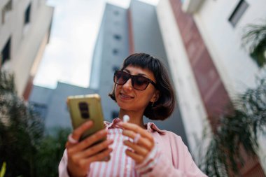 Şehir caddesinde şık giyinmiş, akıllı telefonlu zarif bir kadının portresi. Dışarıda mutlu bir iş kadını. Başarılı bir iş kadını.