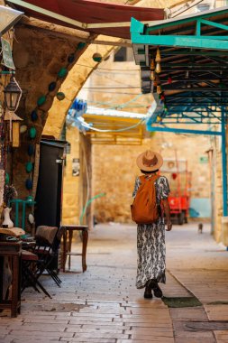 İsrail 'in tarihi Acre şehrini keşfeden şapkalı ve sırt çantalı güzel bir gezgin kız. seyahat ve macera