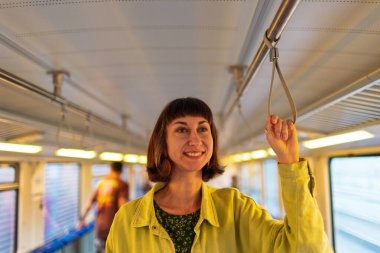 Kız toplu taşıma araçlarını kullanıyor. Trende duran kız. Her gün işe giderken toplu taşıma araçlarını kullanan mutlu ve çekici bir kadın..