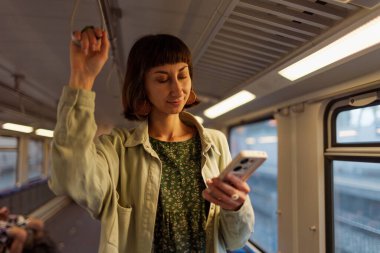 Trende gülümseyen güzel bir kızın portresi. Akıllı telefon kullanıyor, arkadaşlarıyla sohbet ediyor, el ele tutuşan bir kadın. Trenle seyahat eden bir kız..