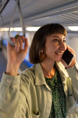 Akşamları toplu taşımada cep telefonuyla konuşan bir kız. Her gün işe giderken toplu taşıma araçlarını kullanan mutlu ve çekici bir kadın. Akıllı telefondan konuşan kız..