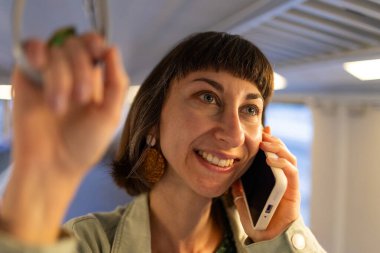 Akşamları toplu taşımada cep telefonuyla konuşan bir kız. Her gün işe giderken toplu taşıma araçlarını kullanan mutlu ve çekici bir kadın. Akıllı telefondan konuşan kız..