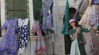 Tatili boyunca markette alışveriş yapan bir kadın kendisi, arkadaşları ve ailesi için sokak mağazasından renkli bir elbise seçiyor. Kız seyahat ediyor..