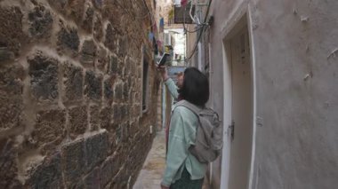 Yolculuk sırasında eski şehrin caddesinde gezen sırt çantalı çekici genç turist mimariye hayran kalıyor, etrafa bakıyor. İsrail 'in Akko kenti