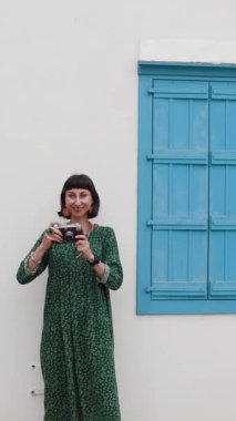 Dikey çekim. Gezgin tatilin tadını çıkarıyor. Kamera ile şehir fotoğraflarını çekiyor. Kadın elleri kamerayı tutuyor ve kentin işaretlerini çekiyor. Seyahat blogcusu fotoğraf çekiyor.