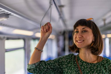 Trende duran kız. Kız toplu taşıma araçlarını kullanıyor. İşe giderken her gün toplu taşıma araçlarını kullanan mutlu ve çekici bir kadın..