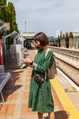 İstasyonun platformunda kamera ve sırt çantasıyla bekleyen genç ve güzel bir kız başvuru formundaki tren saatlerine bakıyor. İyi yolculuklar..