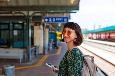 İstasyonun platformunda kameralı ve sırt çantalı genç ve güzel bir kız. İyi yolculuklar..