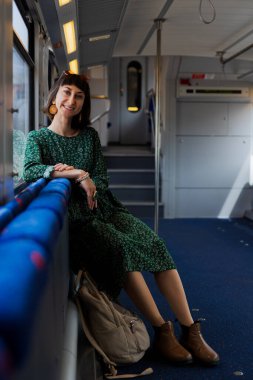 Trendeki kadın pencerenin yanında oturur ve pencereden dışarı bakar. Bir kadın gezgin trenin camından dışarı bakar ve sürmekten zevk alır. bir tren yolcusu.