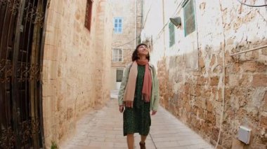 Seyahat sırasında eski şehrin caddesinde yürüyen turistler mimariye hayran kalıyor, etrafa bakınıyorlardı. Ön manzara. İsrail 'in Akko kenti