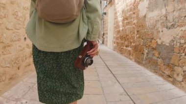 Bir turist elinde kamerayla eski şehrin caddesinde yürüyor ve manzaranın fotoğraflarını çekiyor. Şehirde kamerası olan bir kız. Seyahat ve macera.