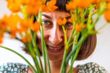 Büyük bir buket çiçekle çekici bir esmer. Ön planda çiçekler. Çiçekli güzel kız. Çiçekli sanatsal portre.