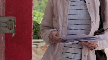 Sokakta bir kız posta kutusunun yanında duruyor ve zarflara bakıyor. Posta alıcısı. Zarflı bir kız.