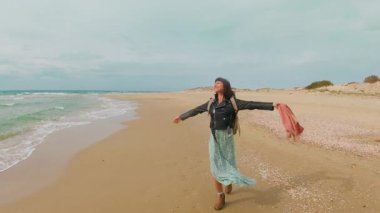 Boş sahilde yürüyen mutlu bir genç kız. Kaygısız kadın denizin dibinde dinleniyor ve özgürlüğün tadını çıkarıyor. Seyahat, tatil, açık hava eğlencesi..