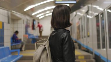 Metroda treni bekleyen kız. Metroda gülümseyen ve kameraya bakan şık bir kız..