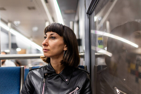 пассажир общественного транспорта. Молодая женщина едет в современном вагоне метро. Красивая девушка в куртке в метро.