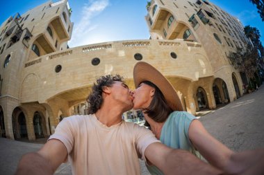 Yaz kıyafetleri içinde aşık genç bir çift şehir caddesinde yürürken öpüşüp selfie çekiyorlar. Sokakta öpücük.