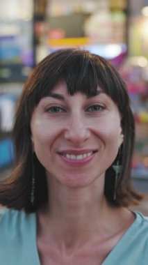 Dikey çekim. Şehrin sokaklarında gülümseyen mutlu genç bir kadının portresi.. 