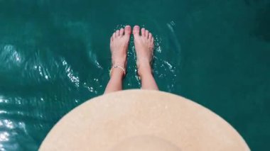 Yaz havası. Güzel ince bacakları olan bir kadın yaz güneşinin tadını çıkarırken, şapkalı bir kadın bacaklarını turkuaz suya daldırıyor. Bir kız dinleniyor..
