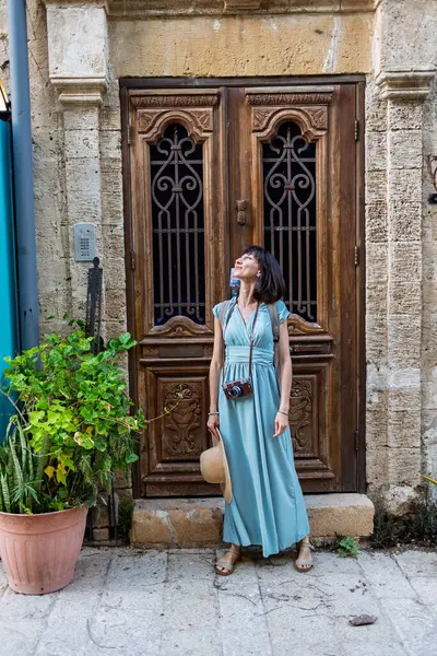 Açık havada yürüyorum. Neşeli gülümseyen stil sahibi kadın turist. Eski şehrin sokaklarında yürüyen bir gezgin. Seyahat ve tatil.