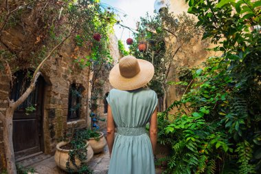 Kız tatilden ve şehirde gezmekten zevk alıyor. Eski Jaffa şehrinde güzel caddelerde yürüyen elbiseli genç bir kadın. İsrail. seyahat ve macera.
