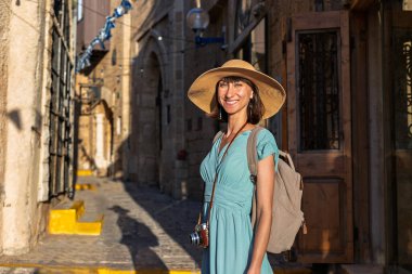 Açık havada yürüyorum. Neşeli gülümseyen stil sahibi kadın turist. Eski şehrin sokaklarında yürüyen bir gezgin. Seyahat ve tatil.