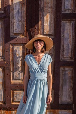 Şehirde saman şapkalı güzel bir genç kadının portresi. Yaz tatili boyunca gülümseyen neşeli genç bir kadın. Mutlu kız güneşten zevk alıyor.