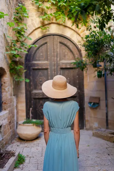 Neşeli gülümseyen stil sahibi bayan turist. Eski Jaffa şehrinde güzel caddelerde yürüyen elbiseli genç bir kadın. İsrail. Seyahat ve macera.