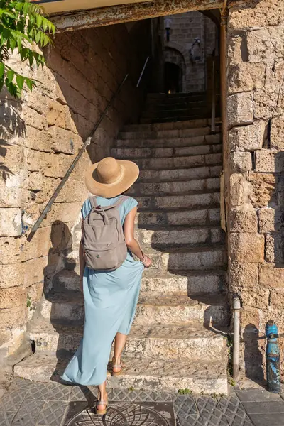 Kız tatilden ve şehirde gezmekten zevk alıyor. Eski Jaffa şehrinde güzel caddelerde yürüyen elbiseli genç bir kadın. İsrail. seyahat ve macera.