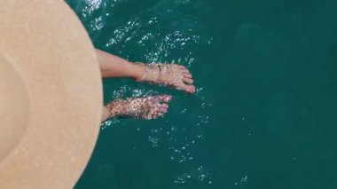 Yaz havası. Güzel ince bacakları olan bir kadın yaz güneşinin tadını çıkarırken, şapkalı bir kadın bacaklarını turkuaz suya daldırıyor. Bir kız dinleniyor..