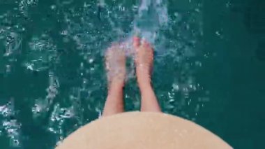 Yaz havası. Güzel ince bacakları olan bir kadın yaz güneşinin tadını çıkarırken, şapkalı bir kadın bacaklarını turkuaz suya daldırıyor. Bir kız dinleniyor..