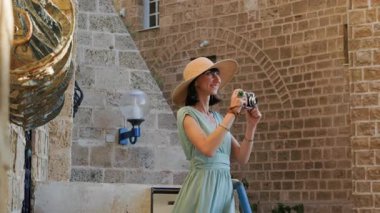 Kameralı kadın fotoğrafçı dışarıda fotoğraf çekiyor. Dışarıdaki kameralı kız. Gezintiler ve şehir yürüyüşleri. Yaşam tarzı, seyahat ve insan kavramı. 