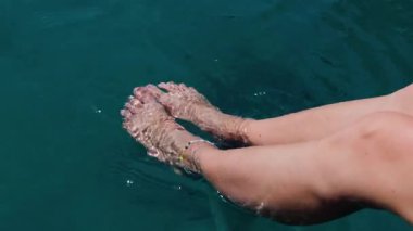 Kız iskelede oturuyor ve ayaklarını denizin mavi ve şeffaf sularına koyuyor. Yaz havası. Güzel ince ve bronzlaşmış bacakları olan bir kadın. Suda dinlenen bir kadın. Ayaklarını turkuaz suya daldıran bir kadın..